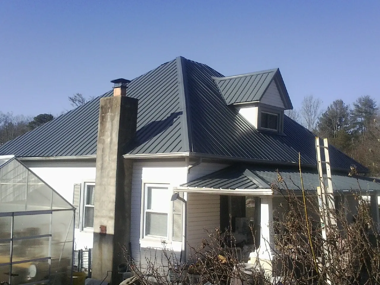Dark blue standing seam metal roof on a white farmhouse with dormer — Slate & Tile Roof Repair by Roofing Brothers in Salvisa