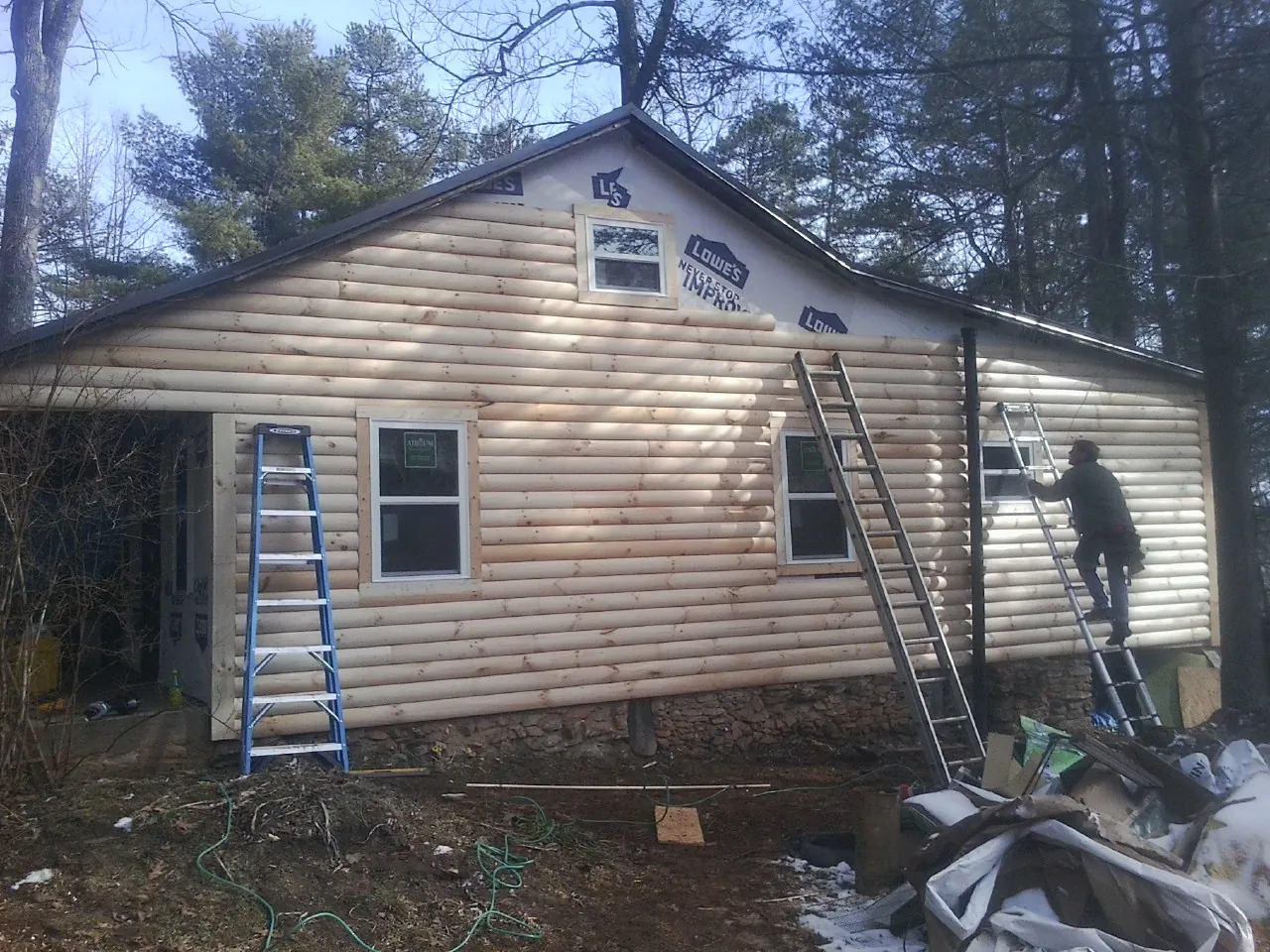 Ladders set against fresh log siding during an exterior remodel in Salvisa