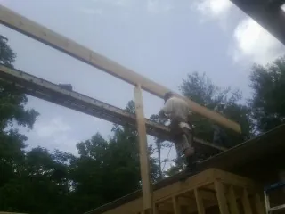 Carpenter setting a ridge beam over a new addition frame — Ice Dam Removal by Roofing Brothers in Salvisa