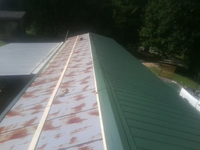 Old rusted panels beside newly installed green metal roofing — Wind Damage Roof Repair by Roofing Brothers in Salvisa