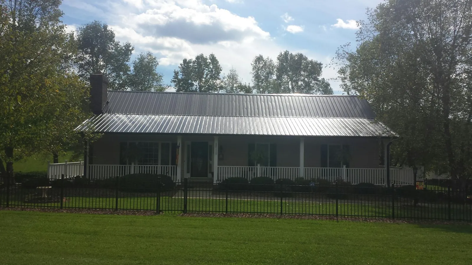 Gray metal roof on a brick ranch with a full width front porch — Gutter Guard Installation work by our crew in Salvisa