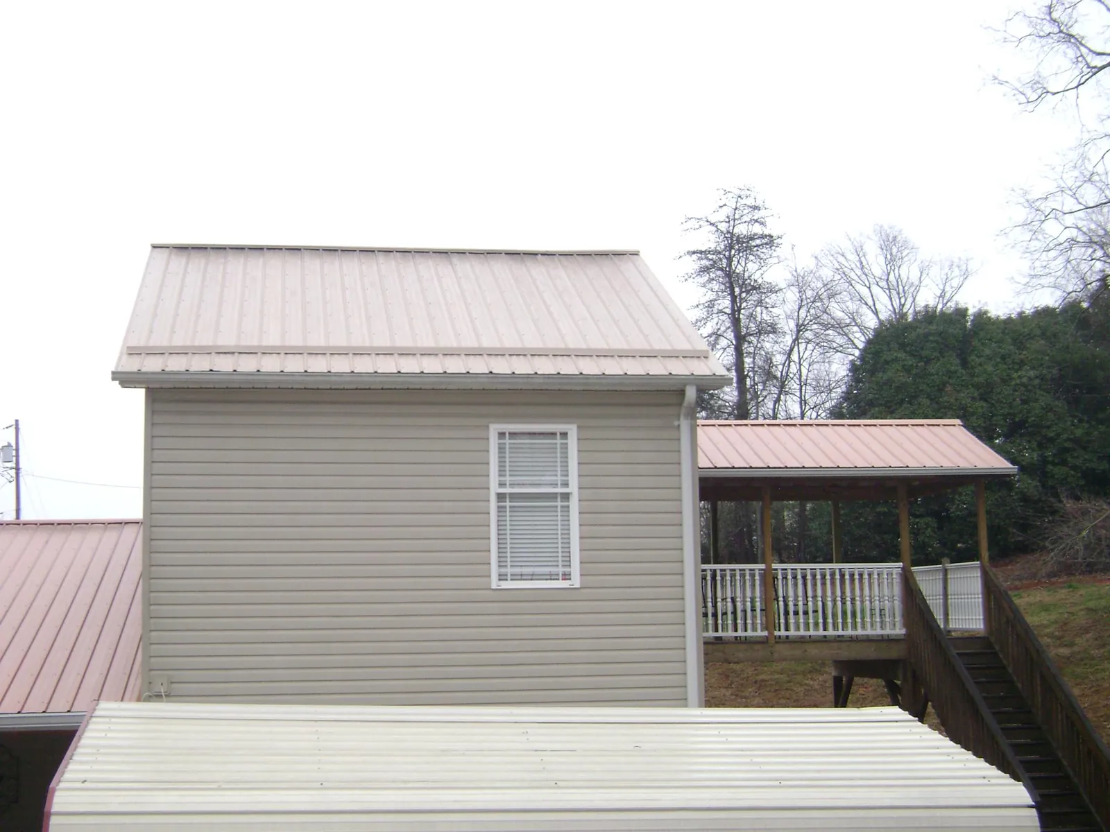 Tan metal roofs on a two story addition and attached porch, from a Roof Replacement job in Salvisa