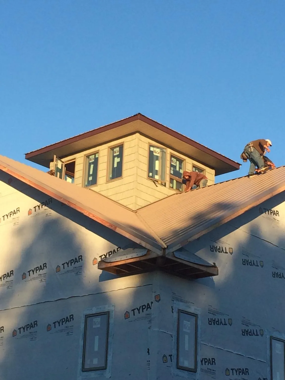 Roofers working around a rooftop cupola on a new metal roof at sunset — Roof Waterproofing in Salvisa by Roofing Brothers